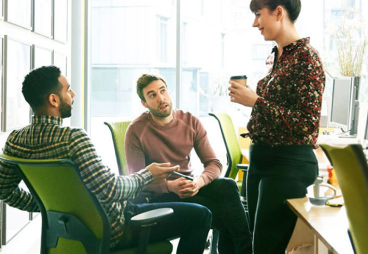 Coworkers casually talking while drinking coffee